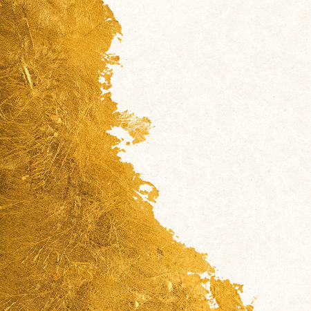 Shiny textured gold leaf foil torn across white paper.の写真素材