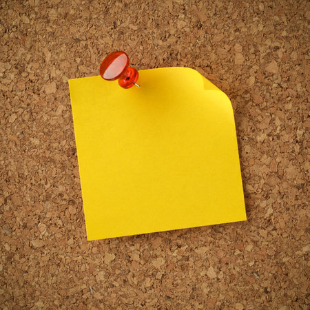 Blank yellow sticky note pinned with red tack. Empty copy space for important office notice, message, or reminder.の写真素材
