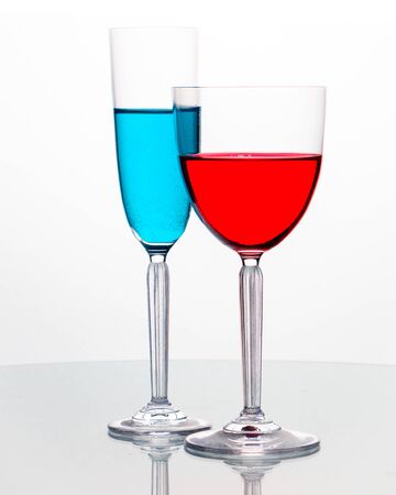 Elegant wineglasses on white background with reflection and vivid colored liquidの写真素材