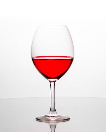 Elegant wineglasses on white background with reflection and vivid colored liquidの写真素材