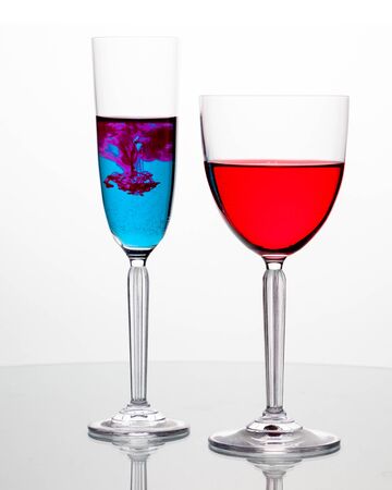 Elegant wineglasses on white background with reflection and vivid colored liquidの写真素材