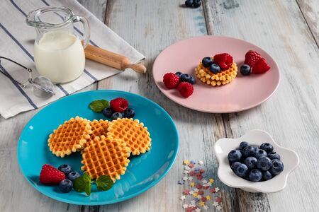 Traditional Belgian waffles with fresh fruit and milk. Rustic kitchen table.の写真素材