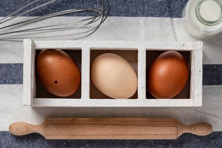 Fresh farmer market brown and white eggs on a kitchen table with utensilsの写真素材