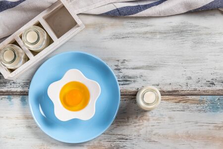 Raw egg on a rustic table top with kitchen utensilsの写真素材