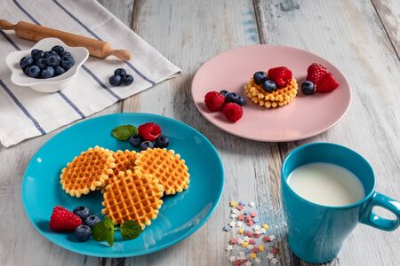 Traditional Belgian waffles with fresh fruit and milk. Rustic kitchen table.の写真素材