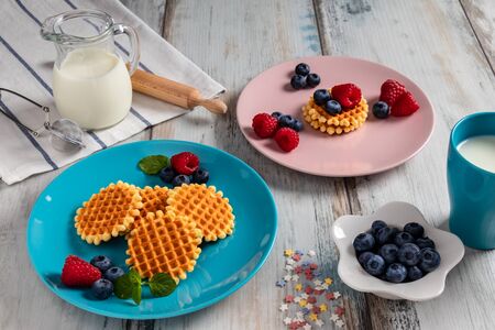 Traditional Belgian waffles with fresh fruit and milk. Rustic kitchen table.の写真素材