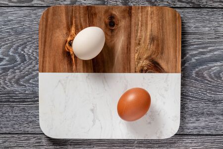 Fresh farmer market brown and white eggs on a kitchen table with utensilsの写真素材