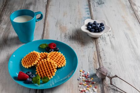 Traditional Belgian waffles with fresh fruit and milk. Rustic kitchen table.の写真素材