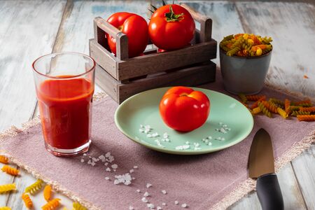 Ripe, fresh tomatoes, salt, pepper and basil with tomato juice and pastaの写真素材