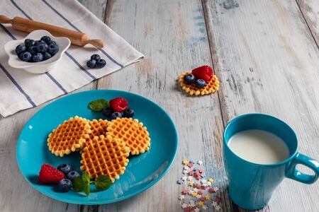 Traditional Belgian waffles with fresh fruit and milk. Rustic kitchen table.の写真素材