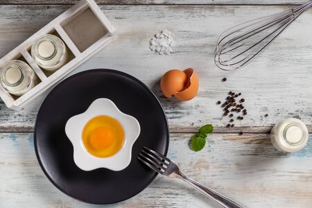 Raw egg on a rustic table top with kitchen utensilsの写真素材