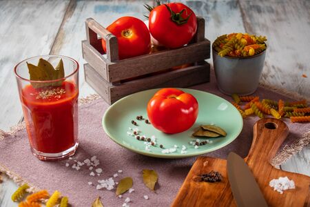 Ripe, fresh tomatoes, salt, pepper and basil with tomato juice and pastaの写真素材