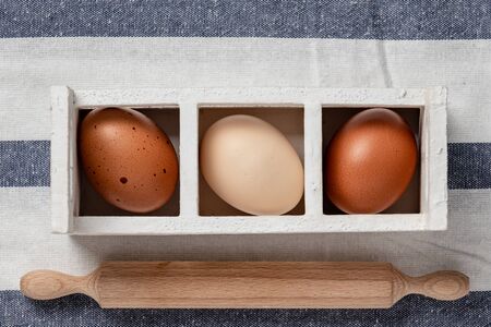 Fresh farmer market eggs on a kitchen table with utensilsの写真素材