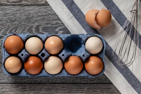 Fresh farmer market brown and white eggs on a kitchen table with utensilsの写真素材