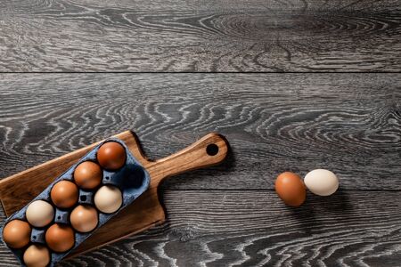 Fresh farmer market brown and white eggs on a kitchen table with utensilsの写真素材