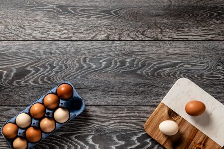 Fresh farmer market brown and white eggs on a kitchen table with utensilsの写真素材