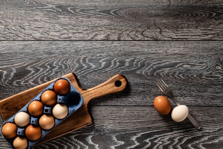 Fresh farmer market brown and white eggs on a kitchen table with utensilsの写真素材