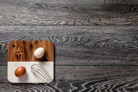 Fresh farmer market brown and white eggs on a kitchen table with utensilsの写真素材