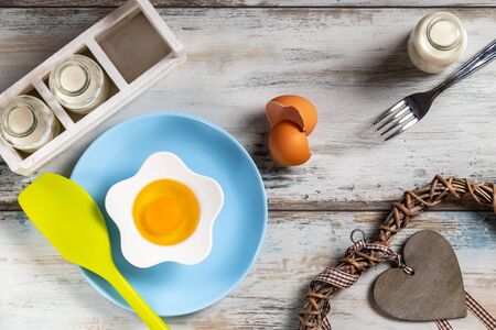Raw egg on a rustic table top with kitchen utensilsの写真素材