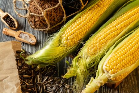 Fresh corn on cobs on rustic wooden table, closeup, zucchiniの写真素材
