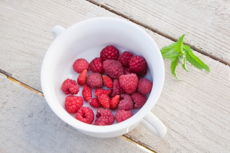 fresh raspberries and strawberries inside a bowl with mint on wooden backgroundの写真素材