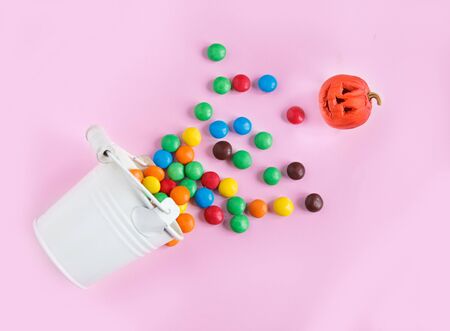 Sweets and a small pumpkin spilled out of a bucketの写真素材