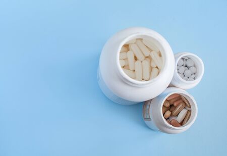 Pills in a three plastic jars, on a blue background. Top view. Copy space for text or advertisingの写真素材