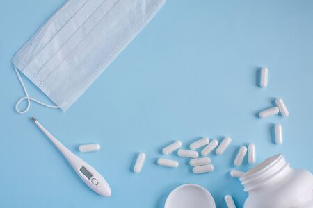 Thermometer, protective mask and pills on blue backgroundの写真素材