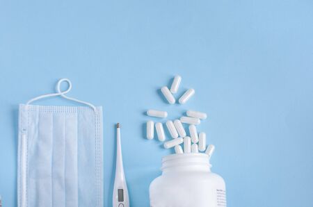 Thermometer, protective mask and pills on blue backgroundの写真素材