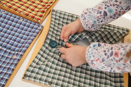 Girl buttoning a montessori dressing frame to develop the dexterity of her fingers.の写真素材