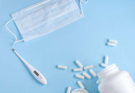 Thermometer, protective mask and pills on blue backgroundの写真素材