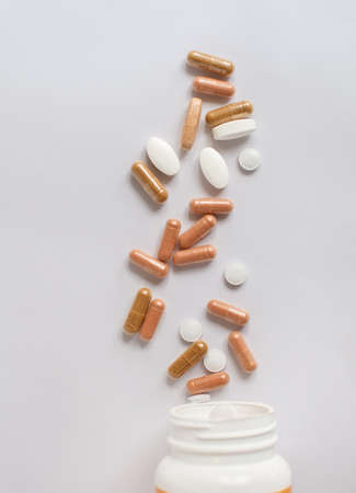 Top view of different pills spilling from white container. Health care.の写真素材