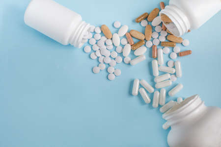 Pills spilled out of the three bottle on blue background. Flat lay witn space for text.の写真素材