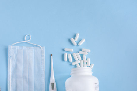 Thermometer, protective mask and pills on blue backgroundの写真素材