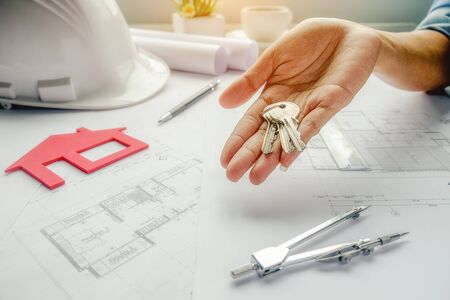 Female hand holds keys on blueprint,Construction concept. Engineering tools.Vintage tone retro filter effect,soft focus(selective focus)の写真素材