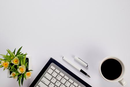 Office desk table with keyboard, notebook, pen, cup of coffee and flower. Top view with copy space (selective focus)

の写真素材