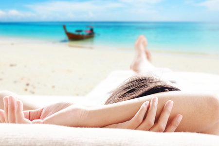 Rear view of asian woman relaxing on a sofa and looking outside beautiful sea background view ....