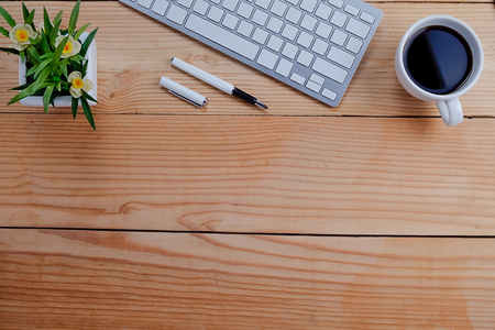 Office desk table with keyboard, pen, cup of coffee and flower. Top view with copy space (selective focus)

の写真素材