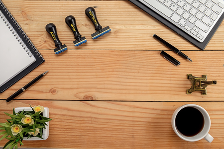 Office desk table with notebook, pen, cup of coffee and flower. Top view with copy space (selective focus)の写真素材