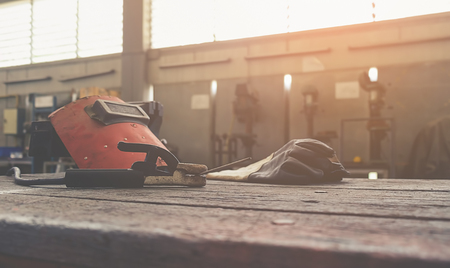 Inverted welding machine welding equipment on a wooden desk with workshop background welding mask leather gloves welding electrodes high-voltage wires with clips set of accessories for arc welding.の写真素材