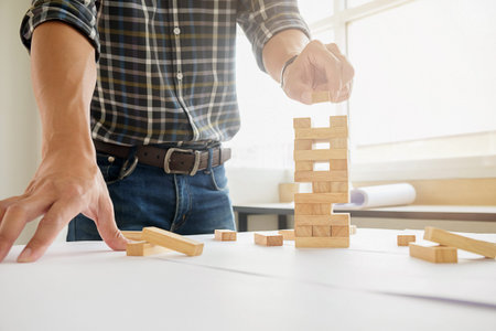 Hand of engineer playing a block wood game on blueprint or architectural project vintage tone. Double exposure of construction site.の写真素材