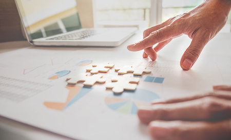 Asian business woman hands on a wooden office desk pick puzzle. Business solutions, success and...