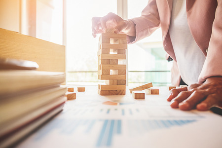 Hand of business woman planning  risk and strategy in business.Businessman gambling placing wooden block on a tower.の写真素材