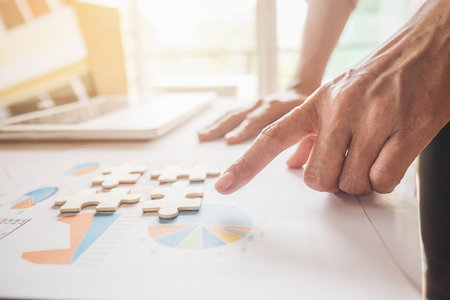 Asian business woman hands on a wooden office desk pick puzzle. Business solutions  success and strategy concept. Businessman hand connecting jigsaw puzzle.Close up photo with selective focus.の写真素材