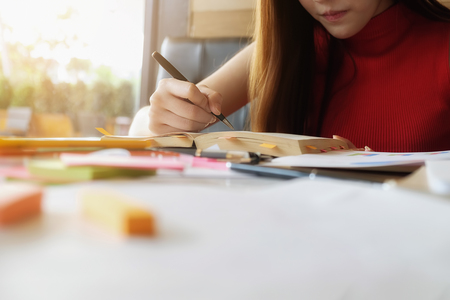 Education concept. Smiling female student working her homework in coffee shop.の写真素材