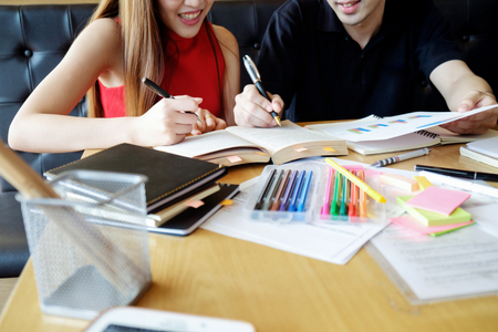Education concept. Students studying and brainstorming campus concept. Close up of students discussing their subject on books, textbooks and writing to notebook. Selective focus.の写真素材