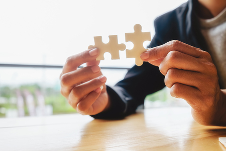 Business woman hands connecting jigsaw puzzle. Business solutions, success and strategy concept. Businessman hand connecting jigsaw puzzle.Close up photo with selective focus.の写真素材