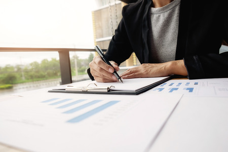 Asian woman manager putting her ideas and writing business plan at workplace, woman holding pens and papers, making notes in documents, on the table in office, vintage color, selective focus.の写真素材