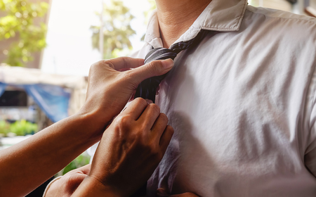 Woman helping her husband to tie his tie before going to work. Vntage color, selective focus. Business concept.の写真素材