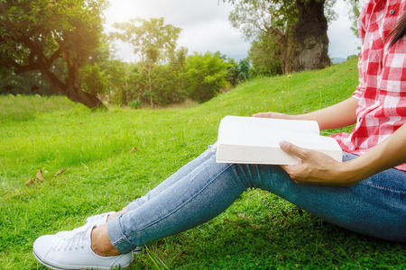 Woman relaxing outdoors looking happy and reading a book. Morning with a book. Relaxing concept. Retro filter effect,soft focus,selective focus.の写真素材